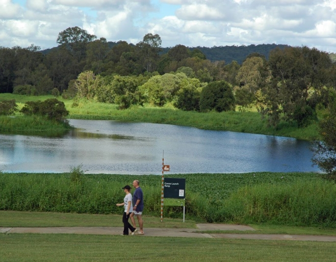 Couple walking along foot and cycle path in Minnippi Parklands next to lagoon.