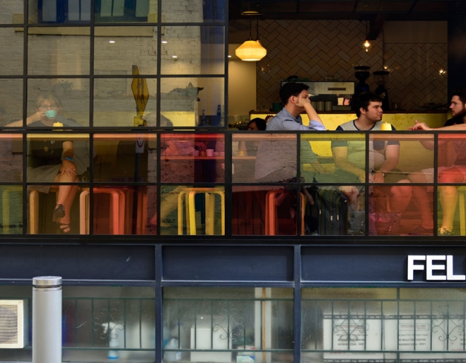 People sitting in Felix Espresso seen through coloured glass on Burnett Lane 