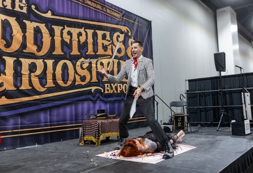 Man on stage juggling knives at the Oddities & Curiosities Expo