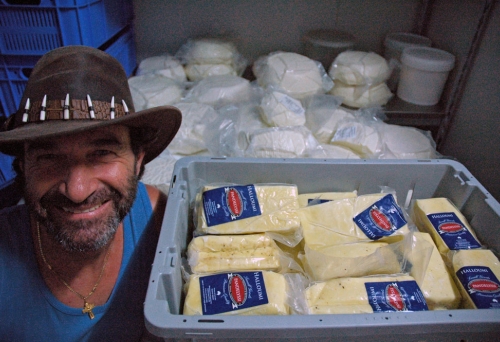 Pandelyssi next to stack of feta and haloumi cheeses inside his factory in Holland Park
