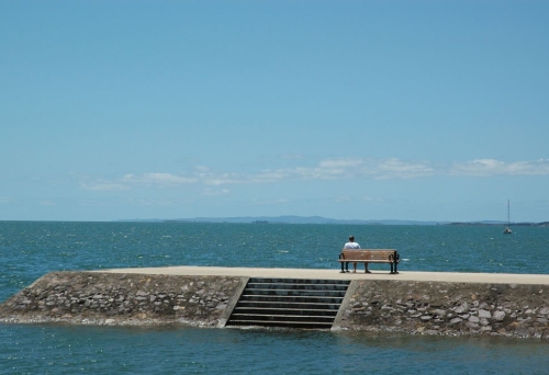 Man sitting on bench looking out to the ocean