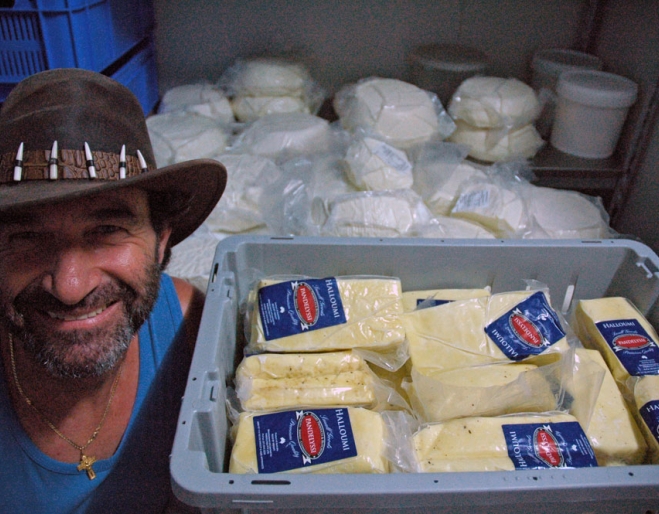 Pandelyssi next to stack of feta and haloumi cheeses inside his factory in Holland Park