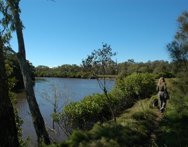 Woman walking on track in Tingalpa Creek Reserve next to creek