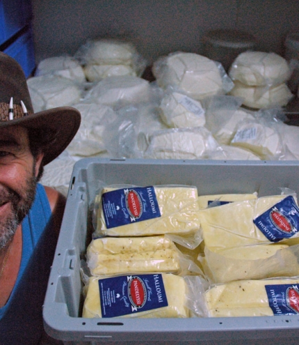 Pandelyssi Cheese Maker Holland Park Pandelyssi next to stack of feta and haloumi cheeses inside his factory in Holland Park