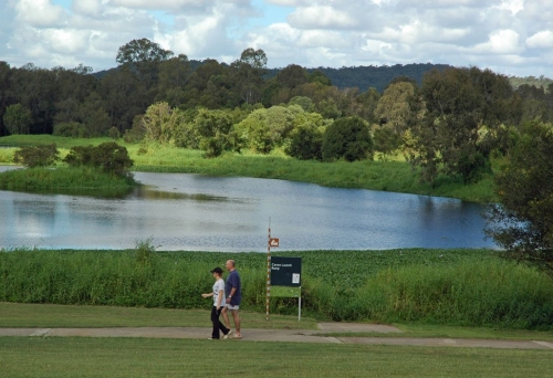 Couple walking along foot and cycle path in Minnippi Parklands next to lagoon.